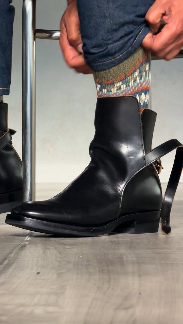 Black leather ankle boots with patterned socks and blue denim jeans