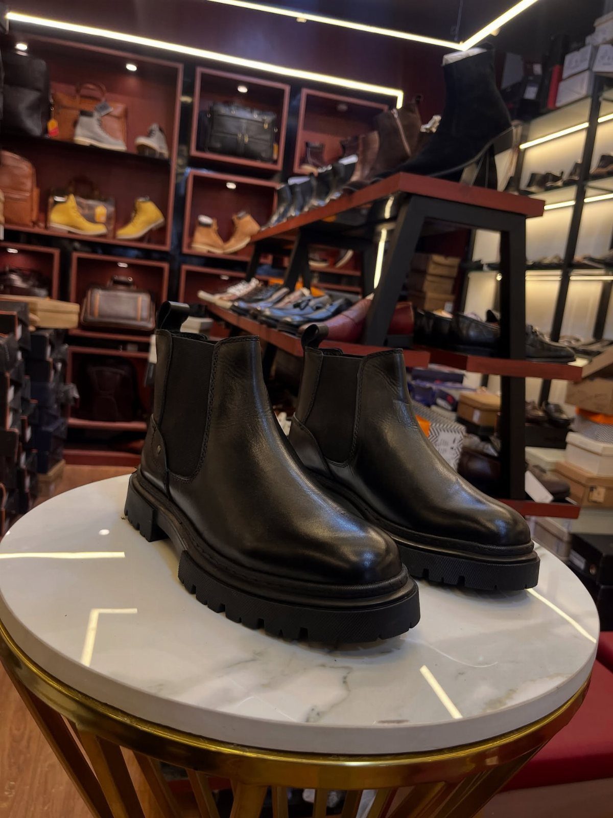 Black leather chunky Chelsea boots on a marble table in a shoe store