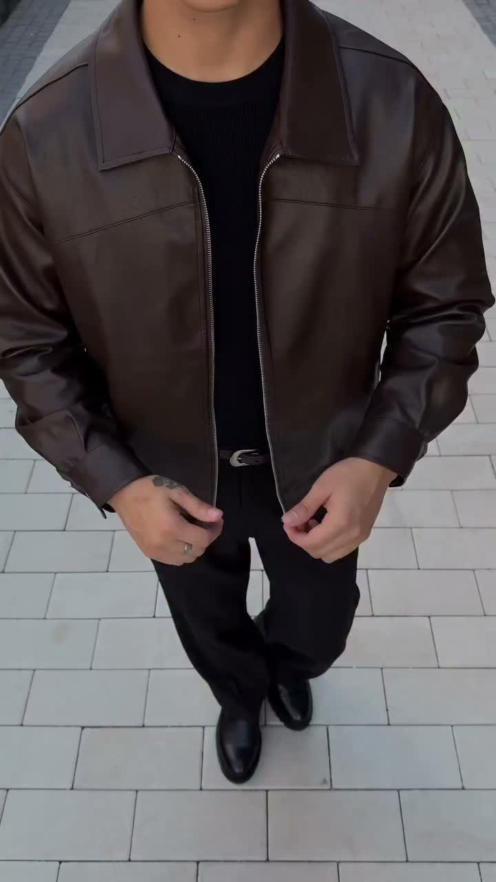 Person wearing a brown leather jacket, black trousers, and black leather boots.