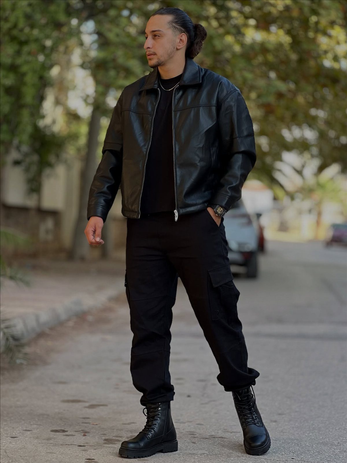 Man wearing a black leather jacket, black cargo pants, and black combat boots.