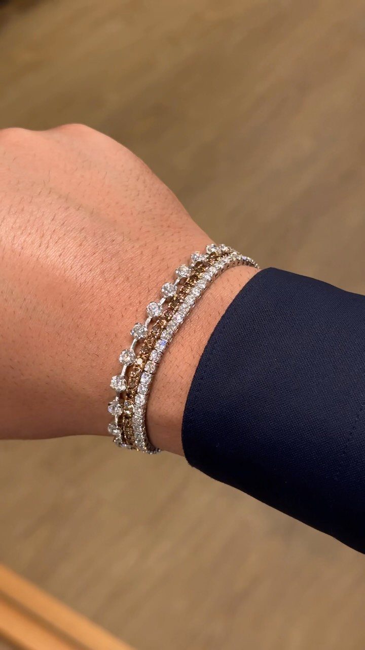 Three diamond tennis bracelets stacked on a man's wrist with a blue suit.