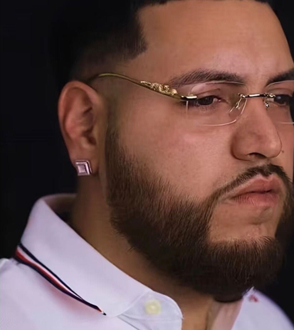 Man with a beard wearing rimless gold glasses and a white collared shirt.