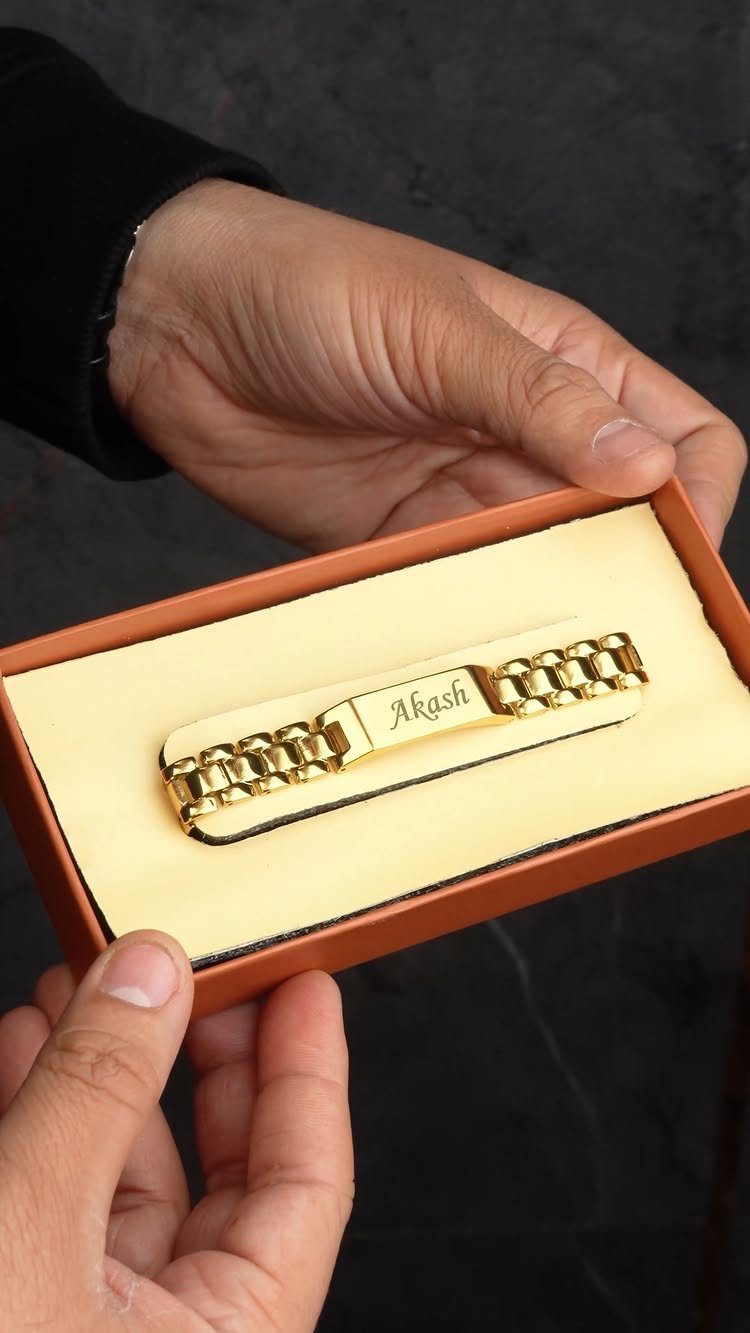 Gold nameplate bracelet engraved with Akash inside an orange jewelry gift box