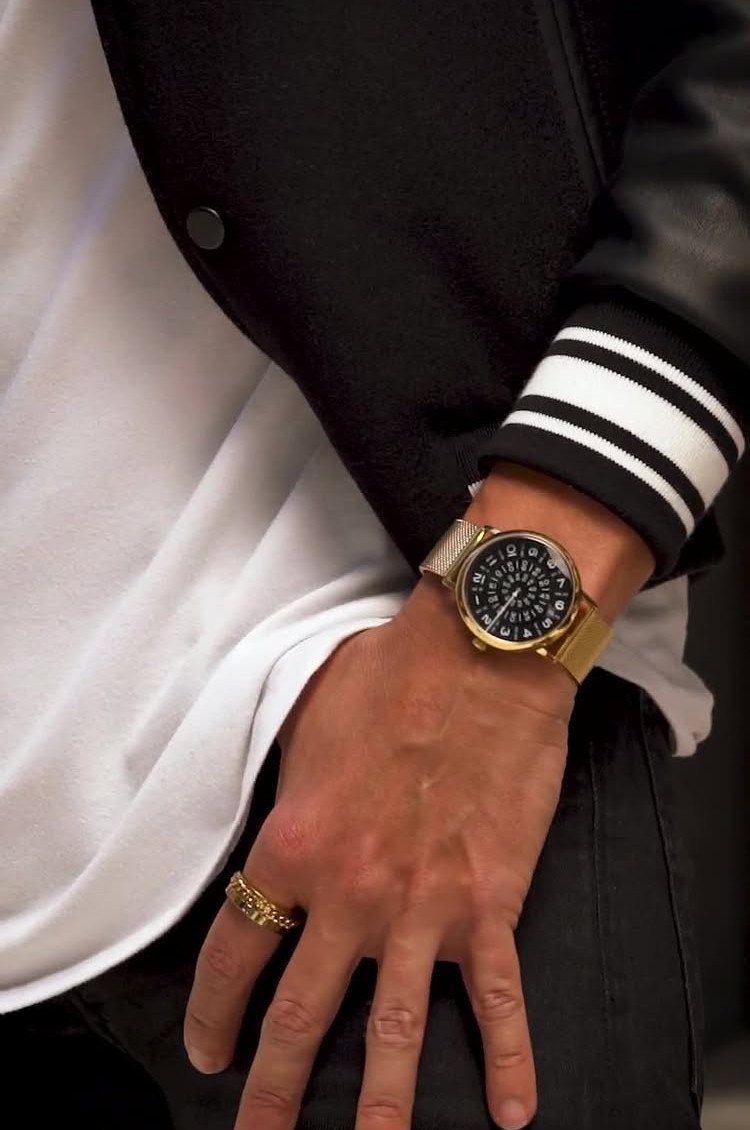 Man's hand wearing a gold ring and a gold watch with black face