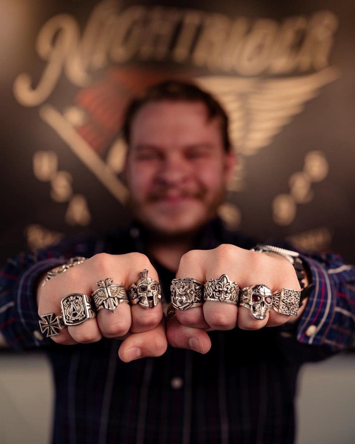 Clenched fists wearing several chunky silver gothic and skull rings on every finger.