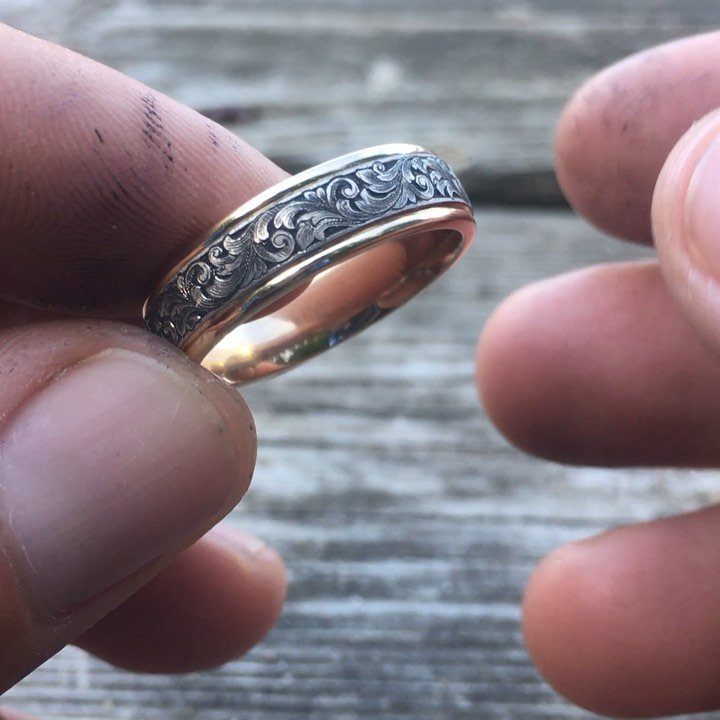 Two-tone gold and silver ring with floral engravings held by dirty fingers