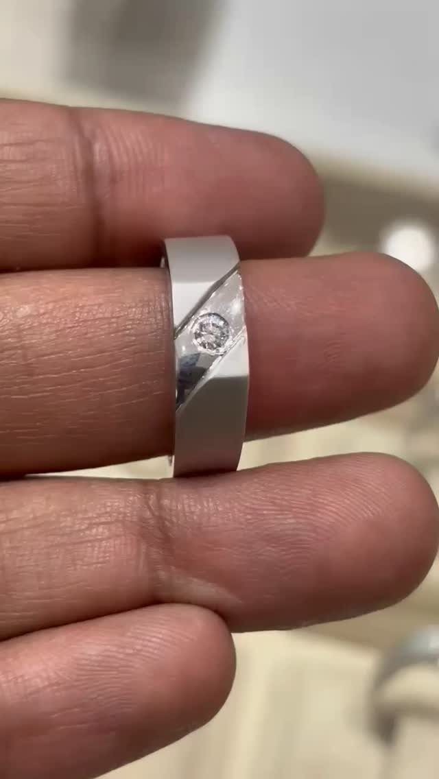 Silver-toned metal ring with a diagonal cut and small diamond on a finger