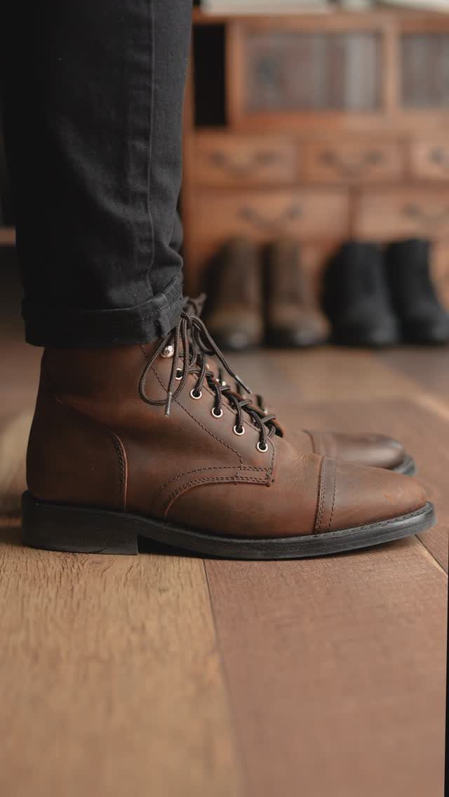 Brown leather lace-up boots worn with dark trousers on a wooden floor
