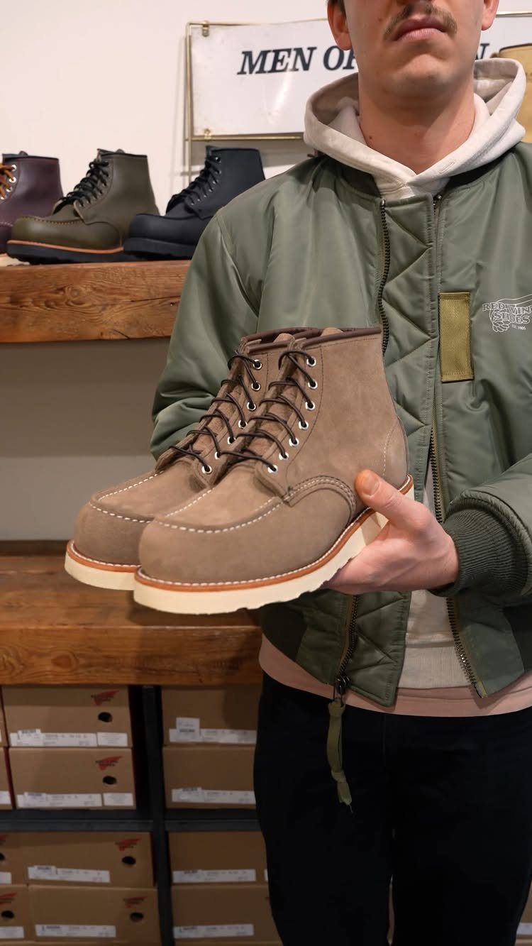 Tan suede moc-toe boots with white wedge soles held by a man.