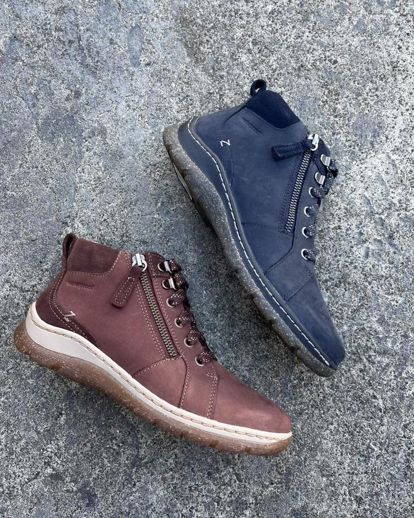 Brown and navy blue sneaker boots with zippers on a concrete floor