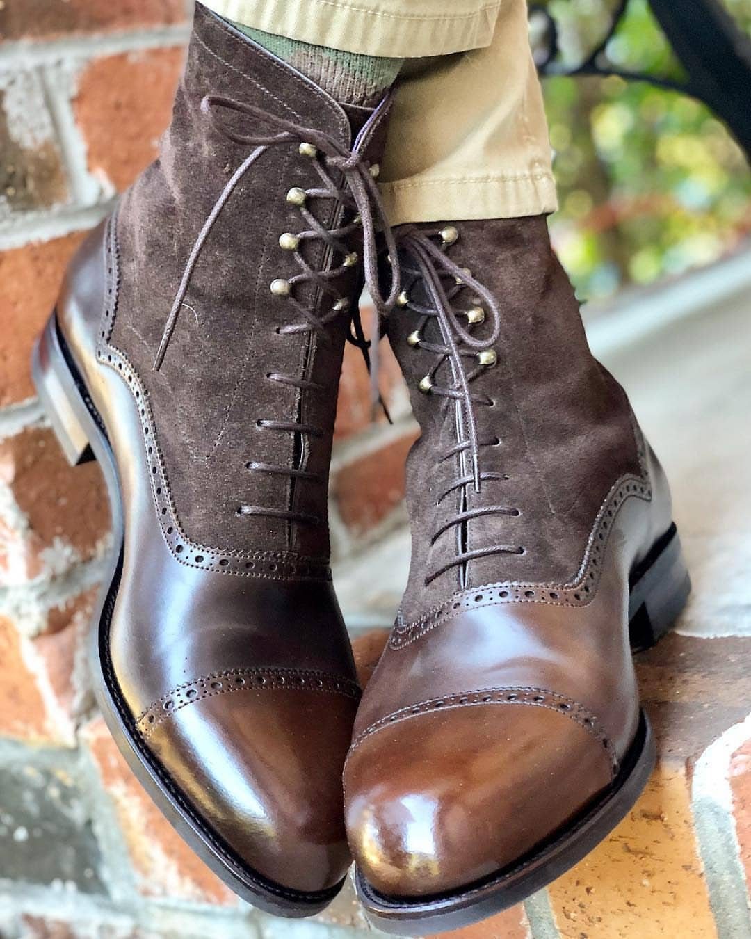 Brown leather and suede lace-up Balmoral boots worn with khaki trousers on bricks.