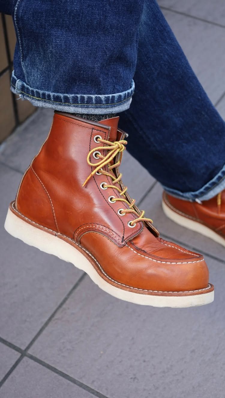 Tan leather lace-up work boots with white soles paired with blue denim jeans.