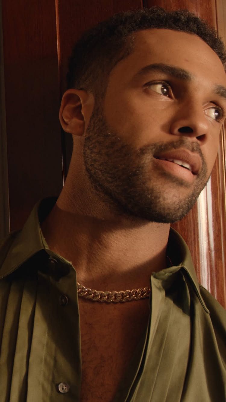 Man with a beard wearing an olive green shirt and gold curb chain.