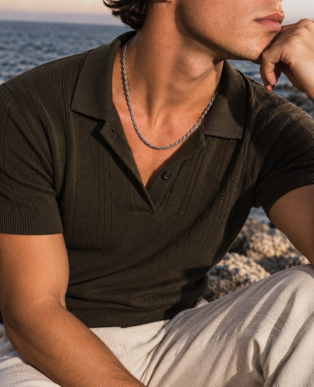 Man wearing a silver rope chain necklace with an olive green polo shirt.