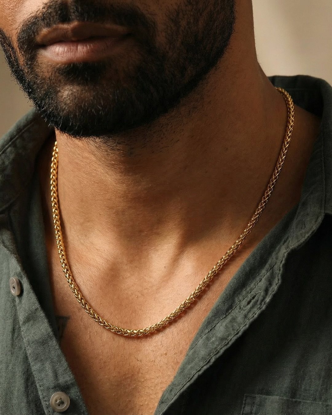 Gold wheat chain necklace worn by a man in a grey shirt