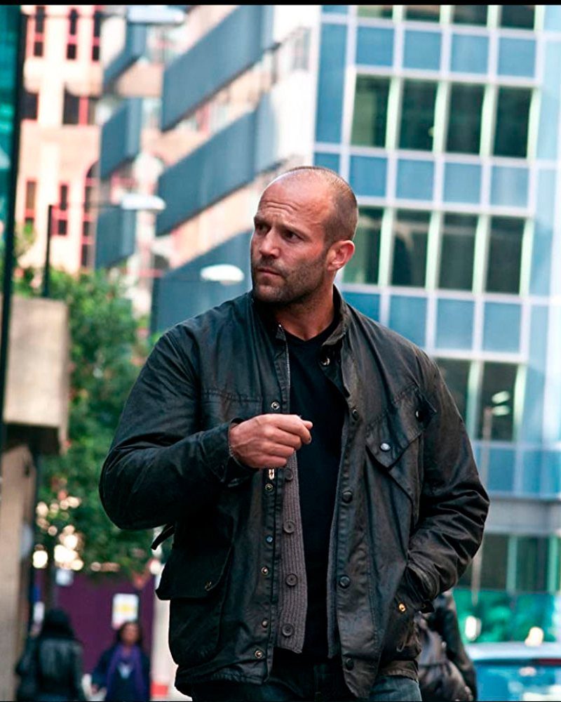 Bald man wearing a weathered brown rugged field jacket in a city setting.