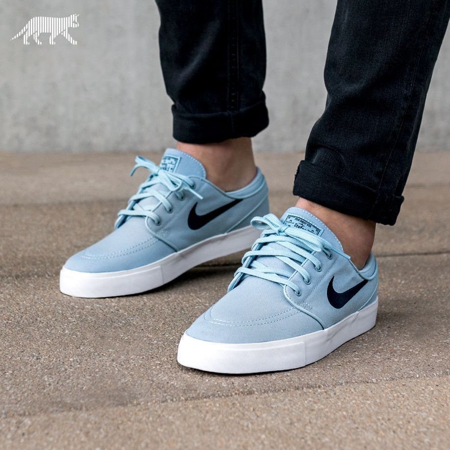 Light blue Nike sneakers with white soles paired with cuffed black jeans.
