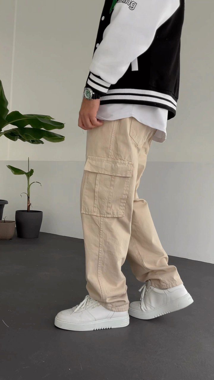 Person wearing beige cargo pants and white sneakers with a varsity jacket.