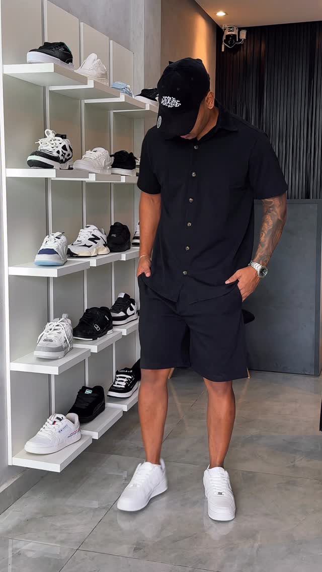 Man in all-black outfit and white sneakers standing in a shoe store
