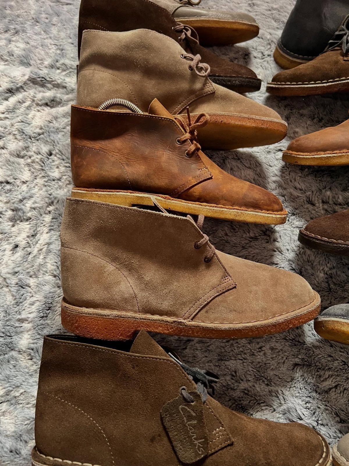 Brown and tan suede desert boots arranged on a grey shag carpet.