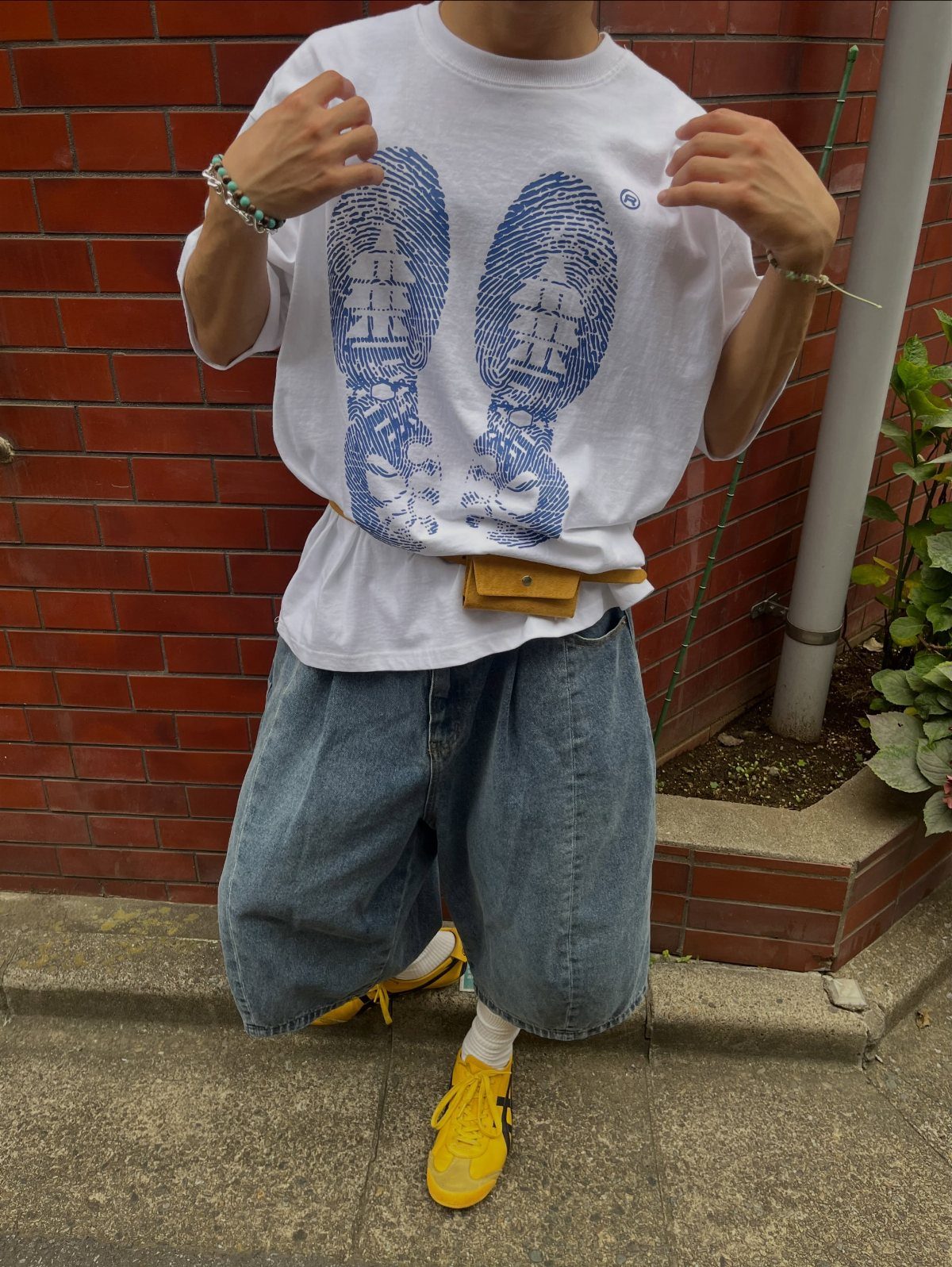Person wearing wide-leg denim shorts, a white graphic t-shirt, and yellow sneakers.