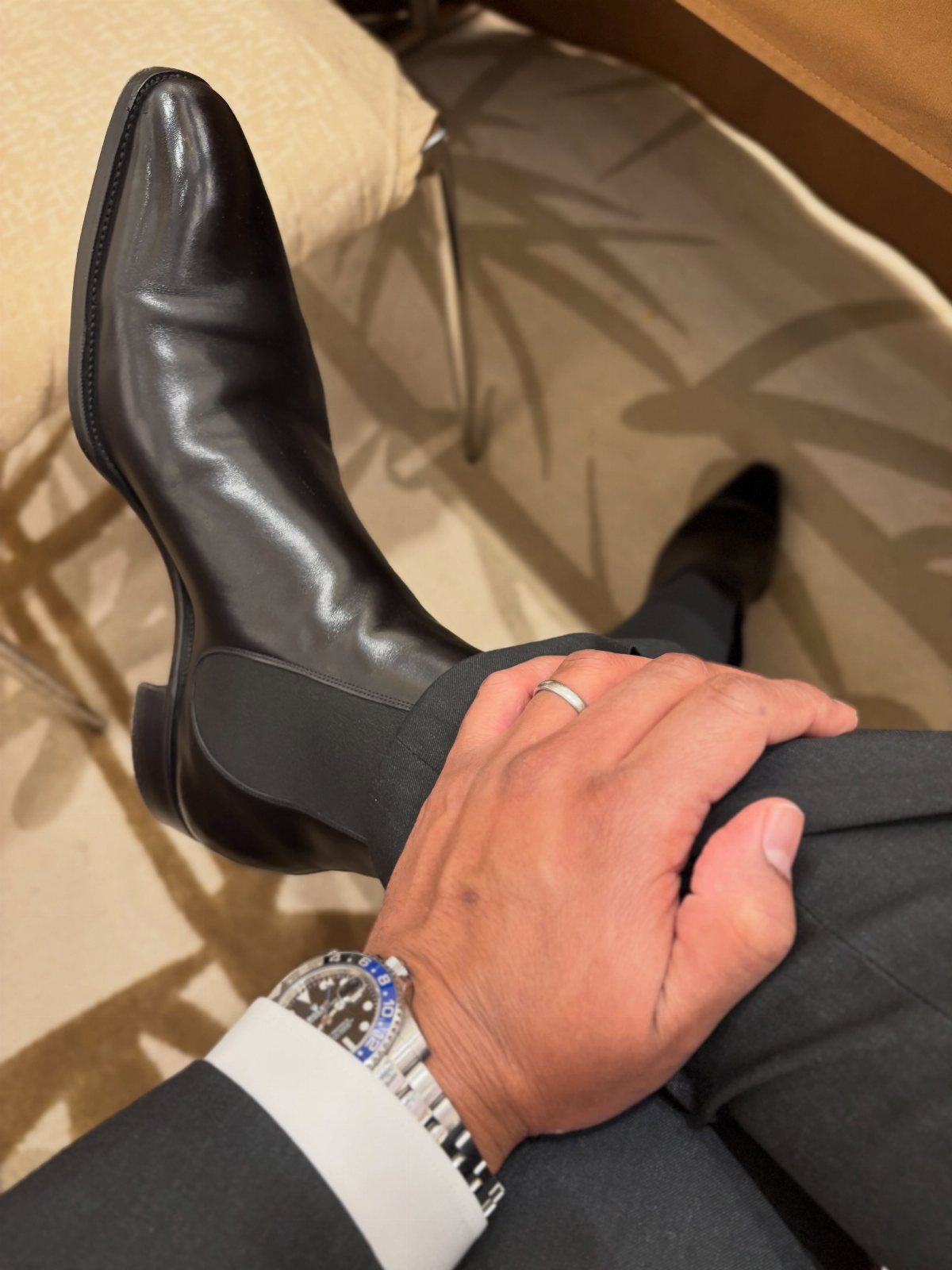 Black leather Chelsea boots paired with dark grey dress pants and a silver watch.