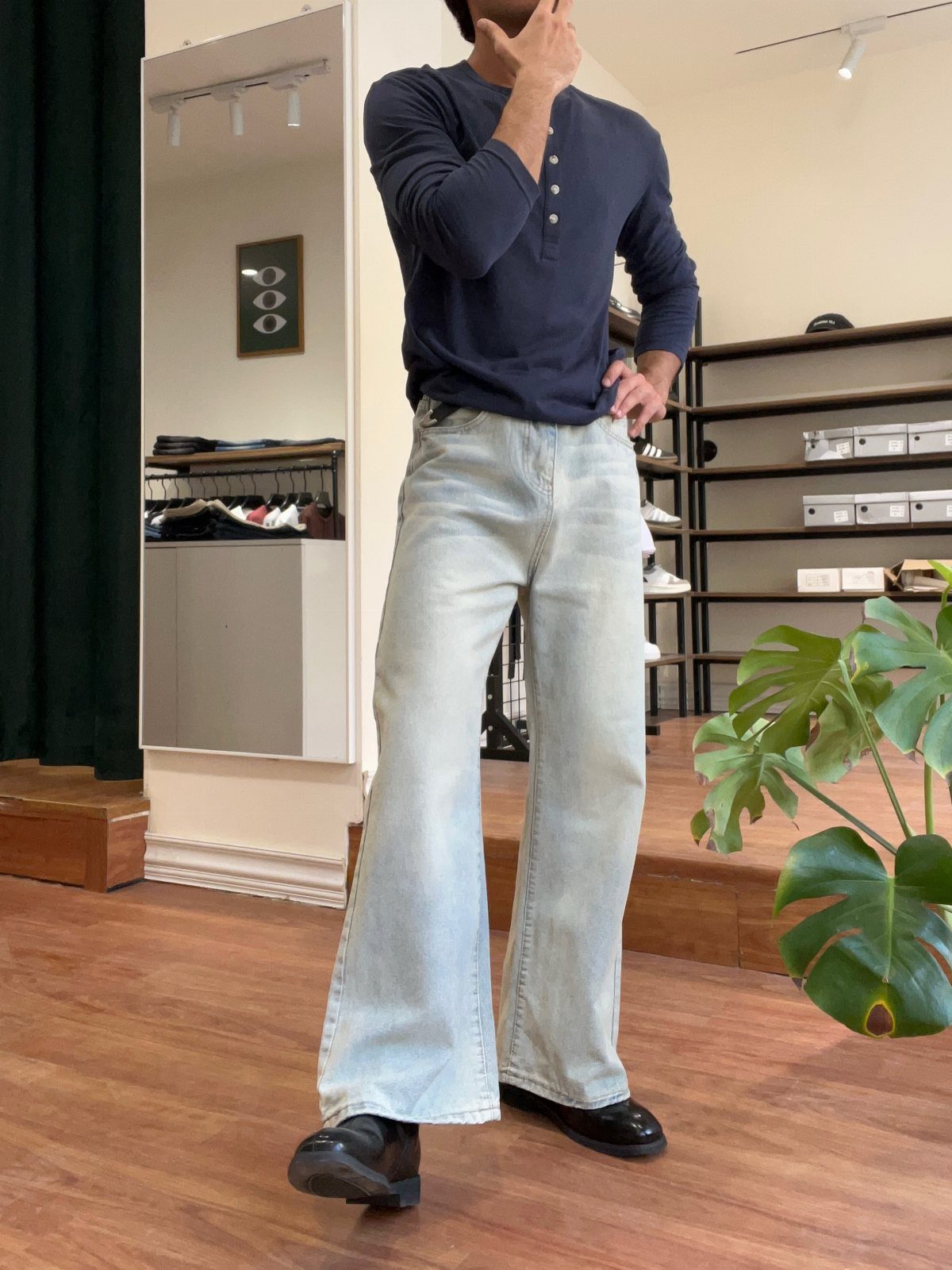 Man wearing navy henley, light-wash wide-leg flared jeans, and black leather boots.