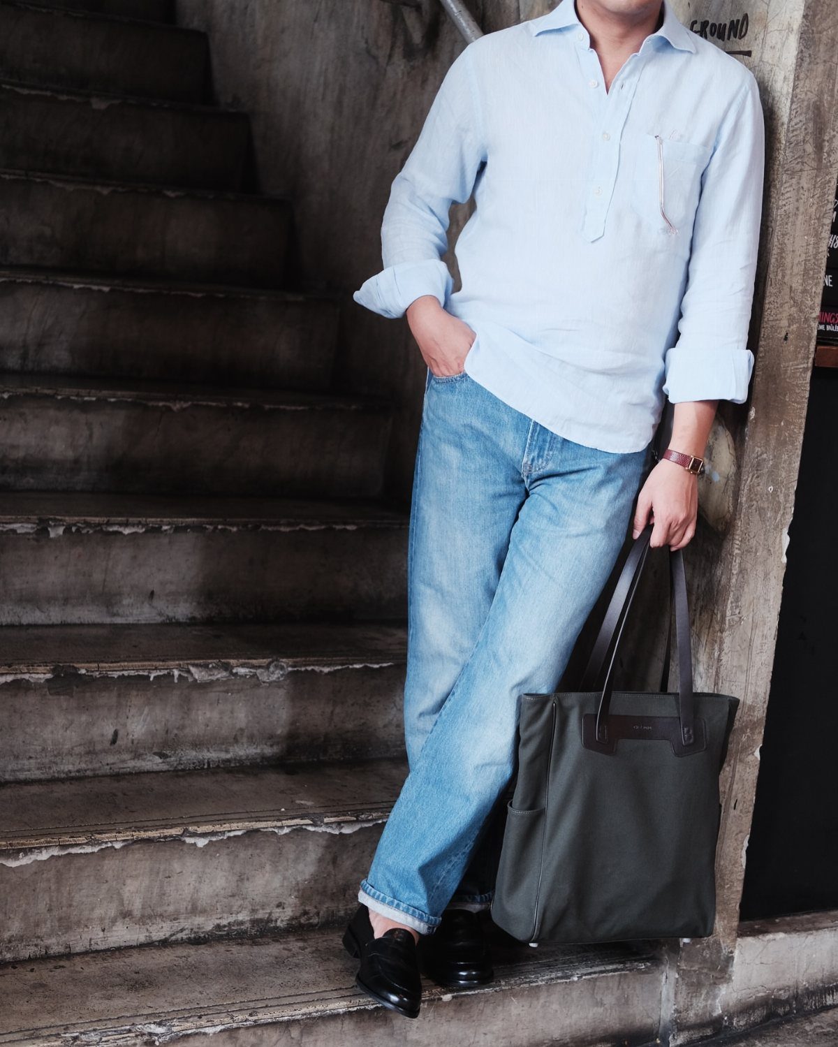 Man in light blue shirt and jeans wearing black leather oxford shoes