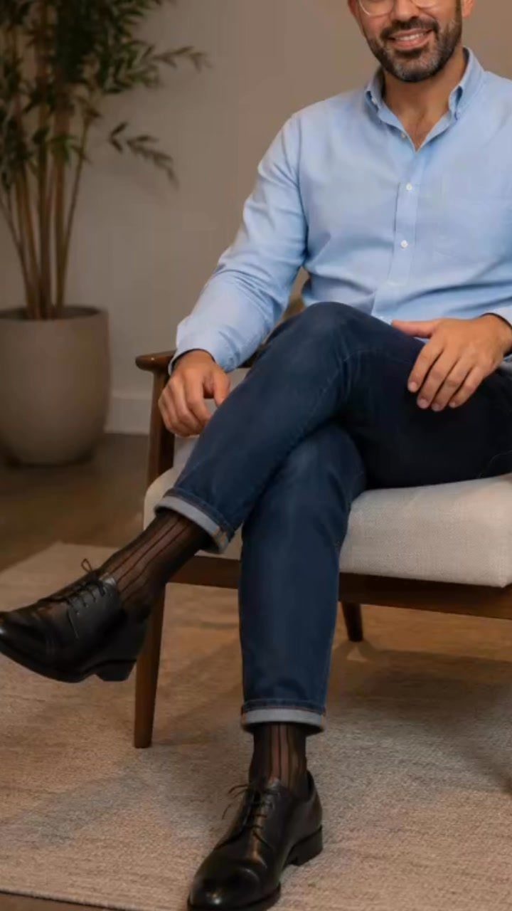 Man wearing a light blue shirt, dark jeans, and black leather oxford shoes.