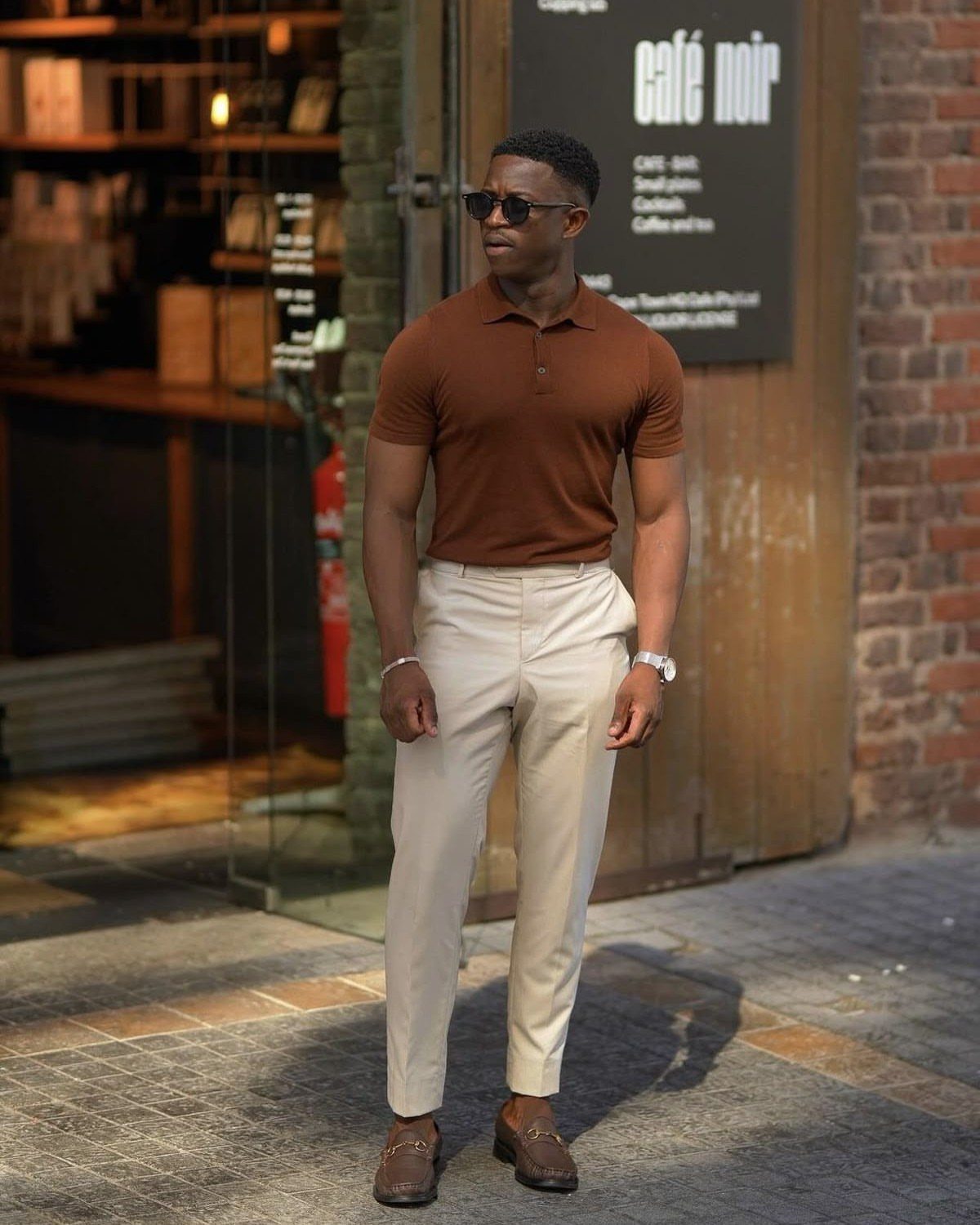 Man wearing brown polo shirt, khaki pants, and brown leather penny loafers outdoors.