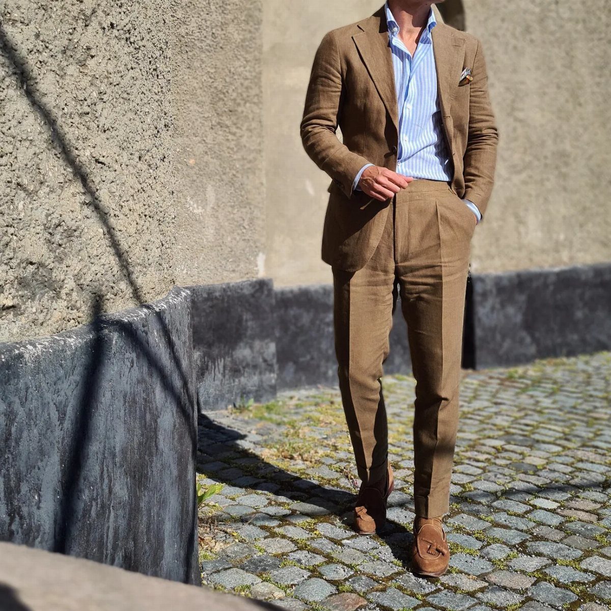 Man in a brown suit and brown suede loafers on a cobblestone street