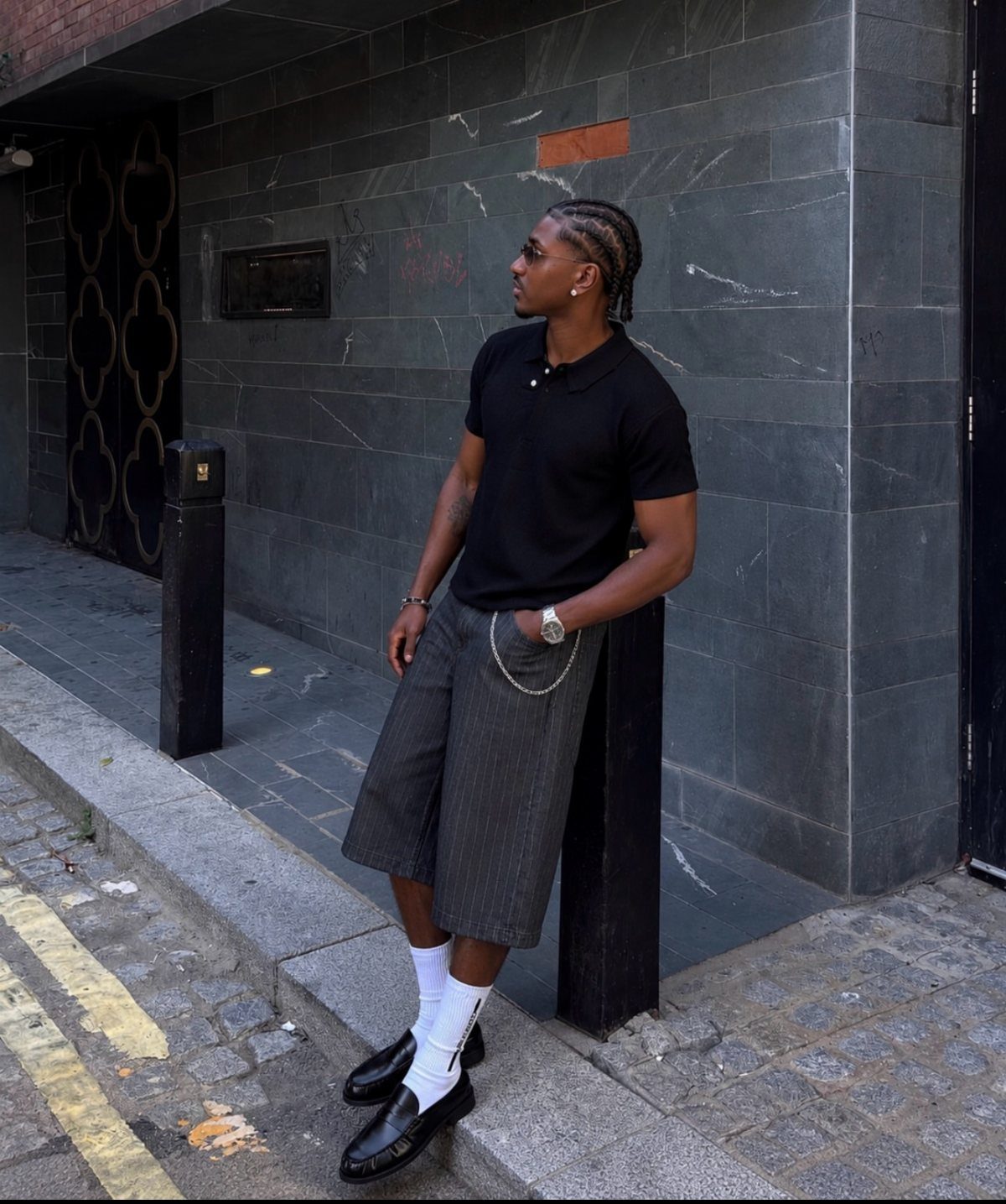 Man in black polo and pinstriped shorts wearing black penny loafers and white socks.