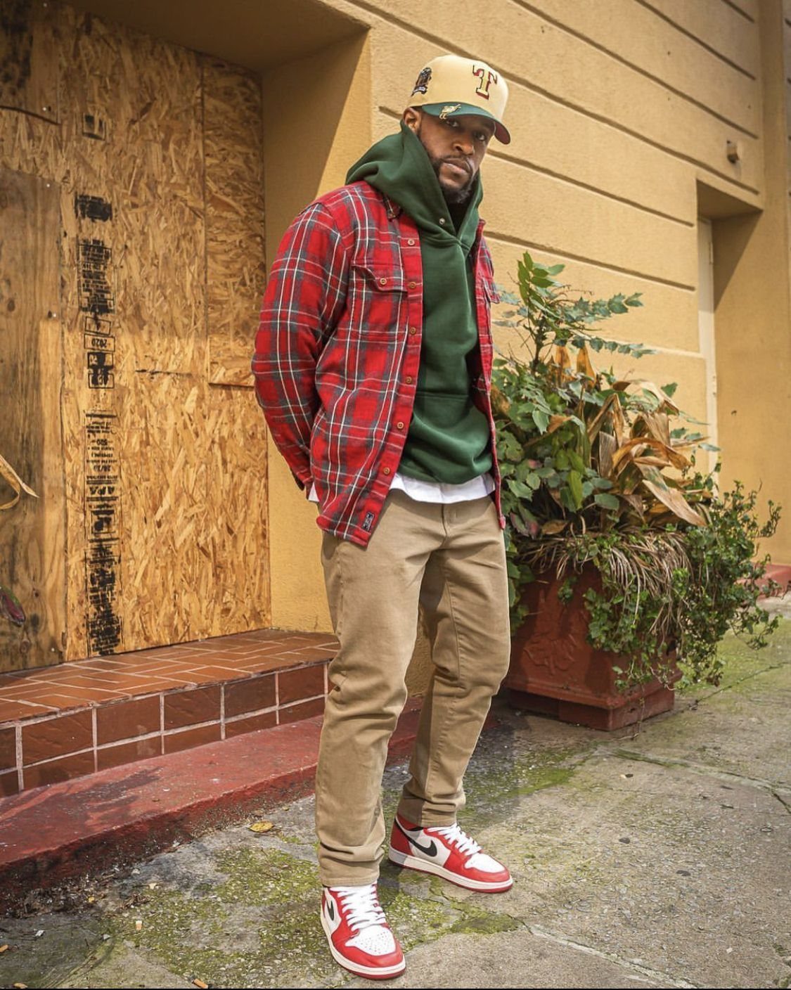 Man wearing red and white sneakers with tan chinos and a red plaid shirt.