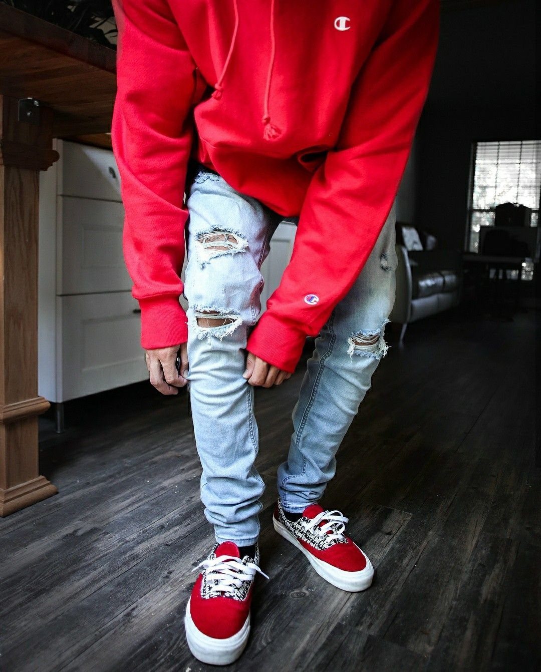 Red and white sneakers paired with light blue ripped skinny jeans and red hoodie