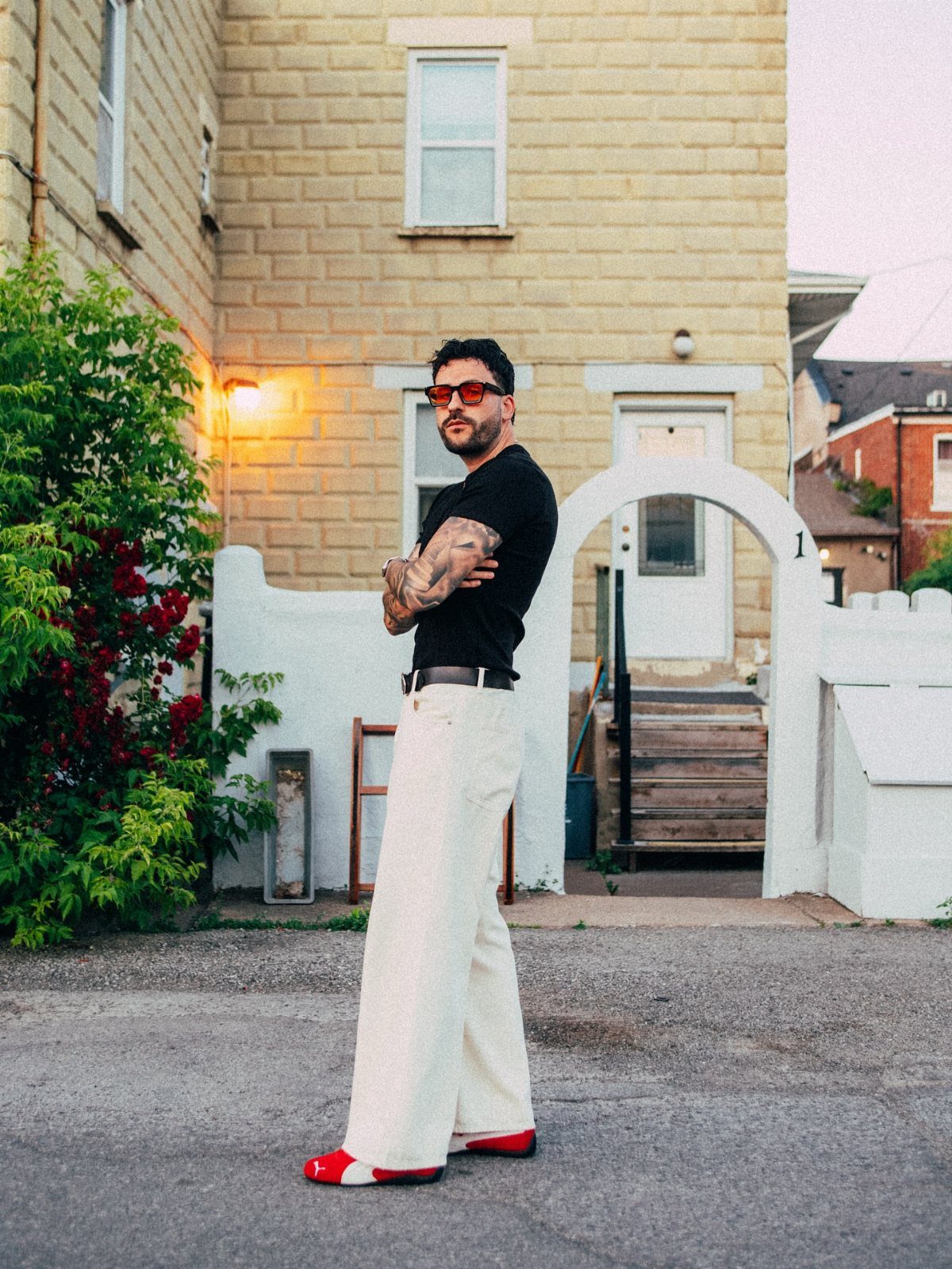Man wearing a black t-shirt, wide white pants, and bright red shoes.