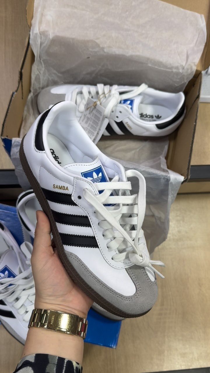 White adidas Samba sneakers with black stripes and grey suede toe caps.