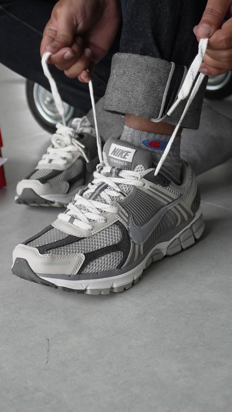 Nike Zoom Vomero 5 sneakers in grey and white worn with cuffed trousers.