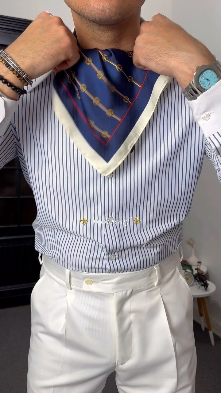 Man wearing a blue patterned silk neck scarf with a striped shirt and white trousers