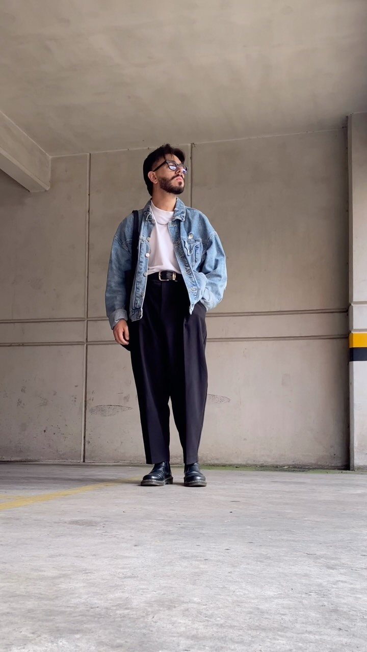 Man in denim jacket and black trousers wearing versatile black leather shoes.