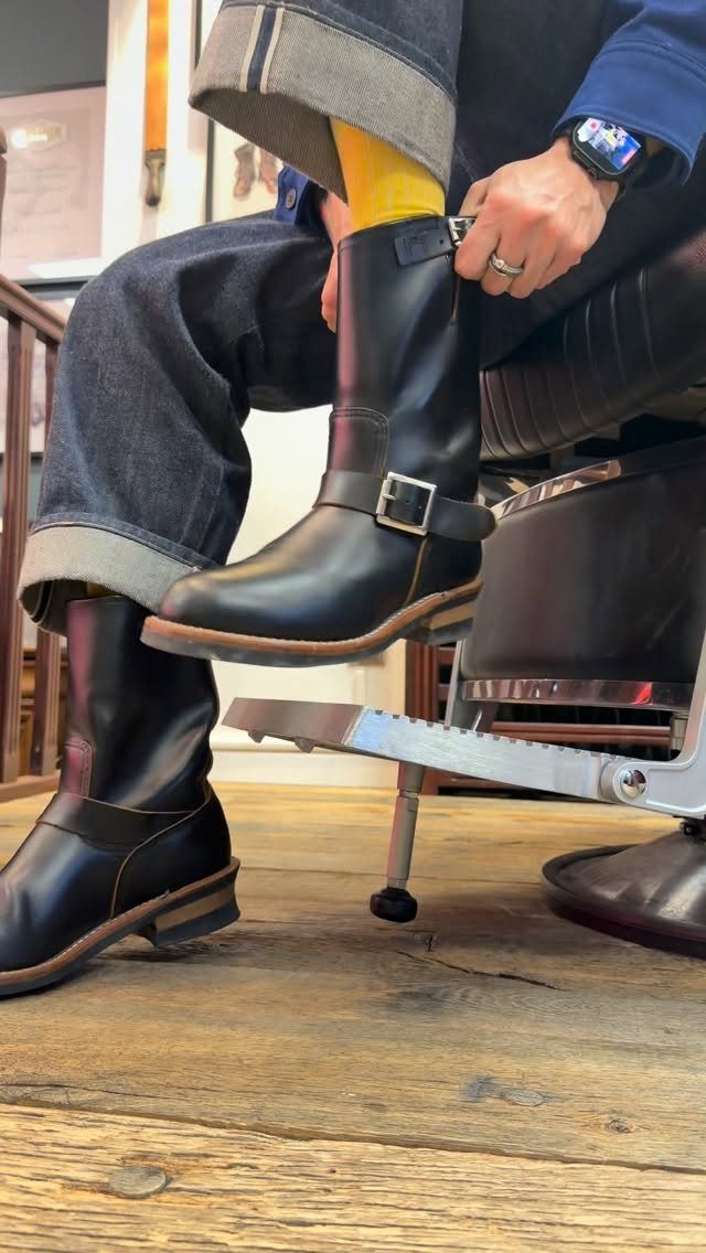 Black leather buckle boots paired with cuffed dark denim jeans and yellow socks.