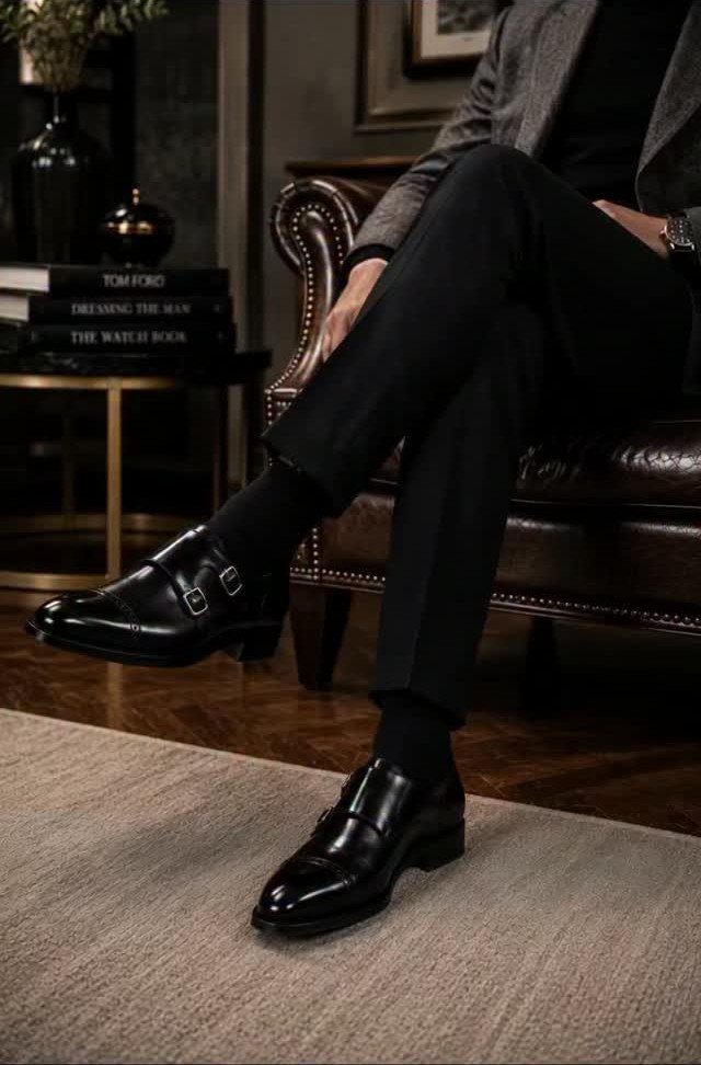 Black double monk strap dress shoes worn with black trousers and socks.