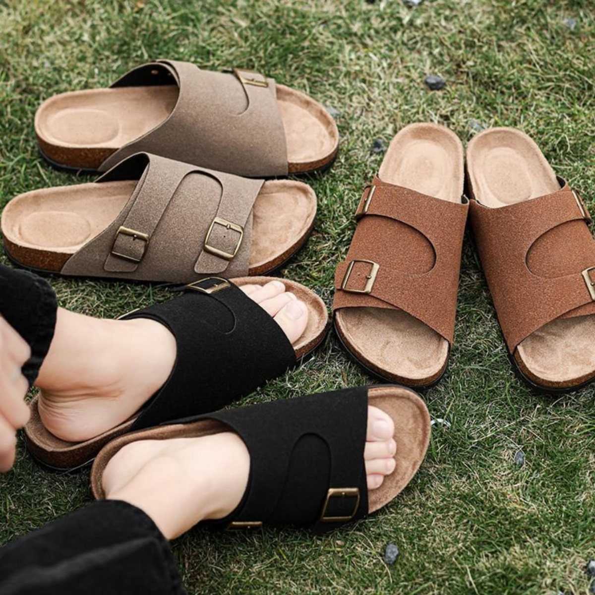 Slide sandals with cork soles in brown and black on green grass.
