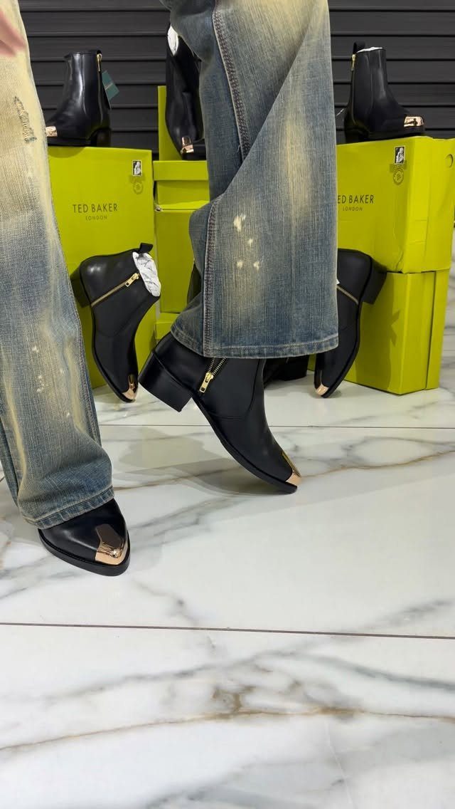 Black leather ankle boots with gold toe caps worn with blue jeans