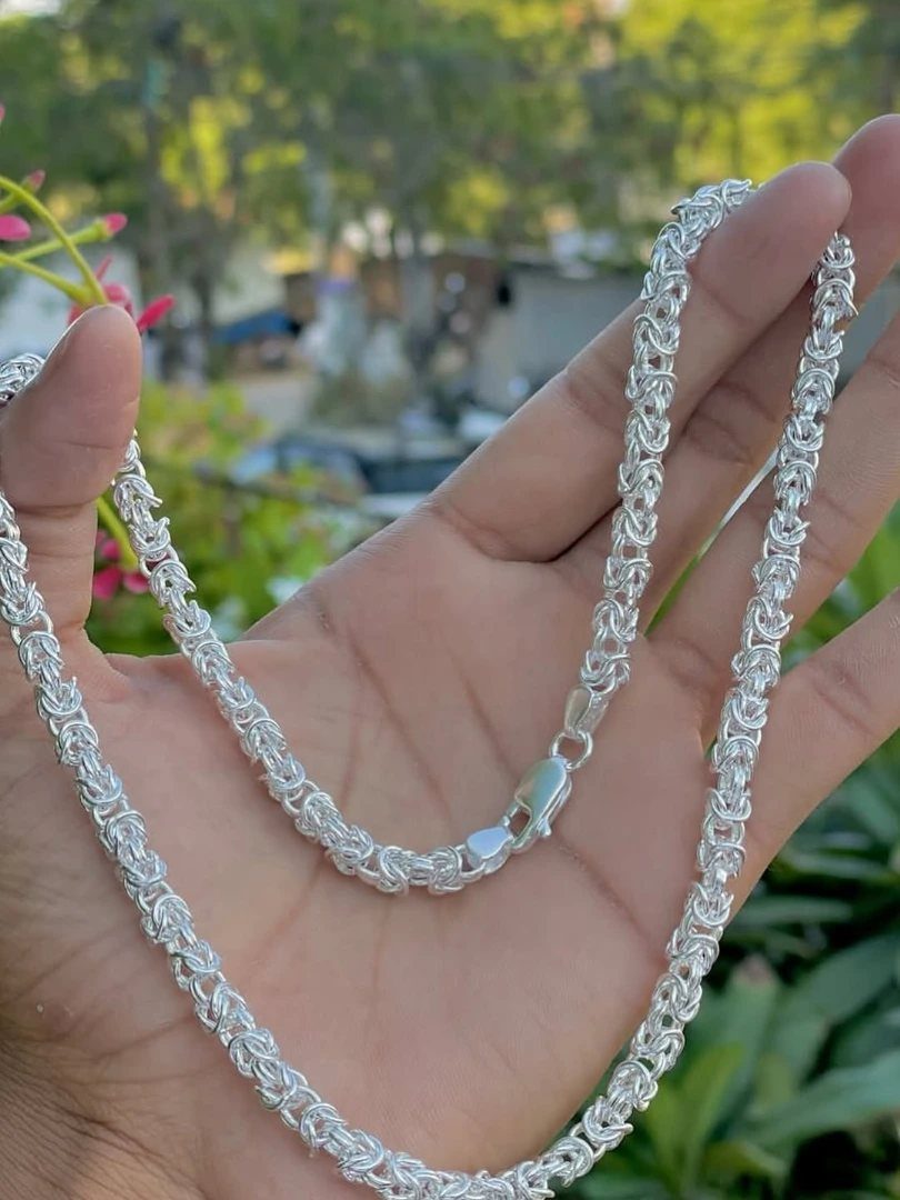 Silver Franco chain with square braided links held in a person's hand outdoors.