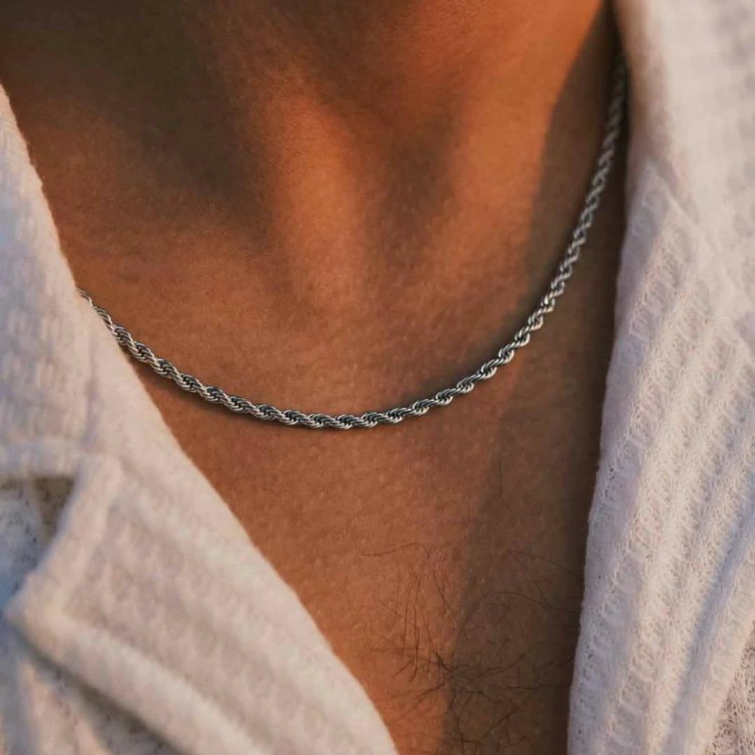 Silver rope chain necklace worn around a person's neck with a white shirt.