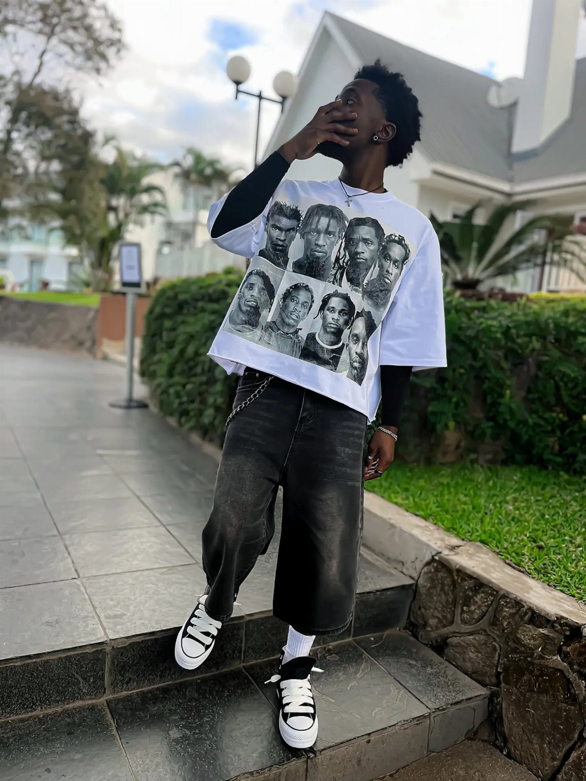 Man in graphic t-shirt and cropped trousers wearing black and white sneakers.