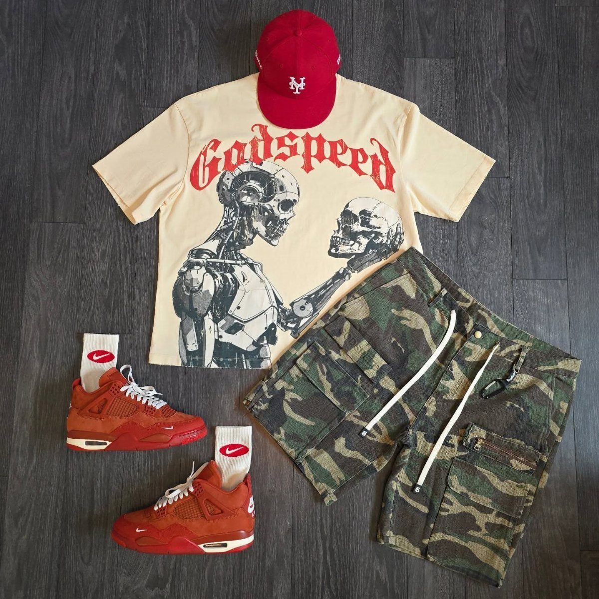 Men's streetwear outfit with red sneakers, camo shorts, and a graphic t-shirt.