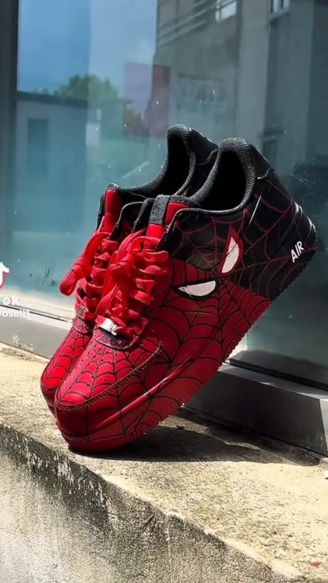 Custom Spider-Man sneakers with red web patterns and mask details on concrete.