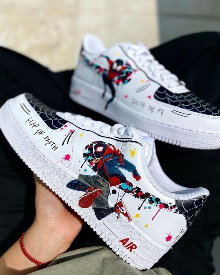 Customized white leather sneakers featuring Spider-Man artwork and black spiderweb patterns.