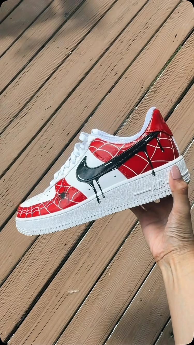 Customized Nike Air Force 1 sneaker with red spiderweb patterns and dripping black swoosh.